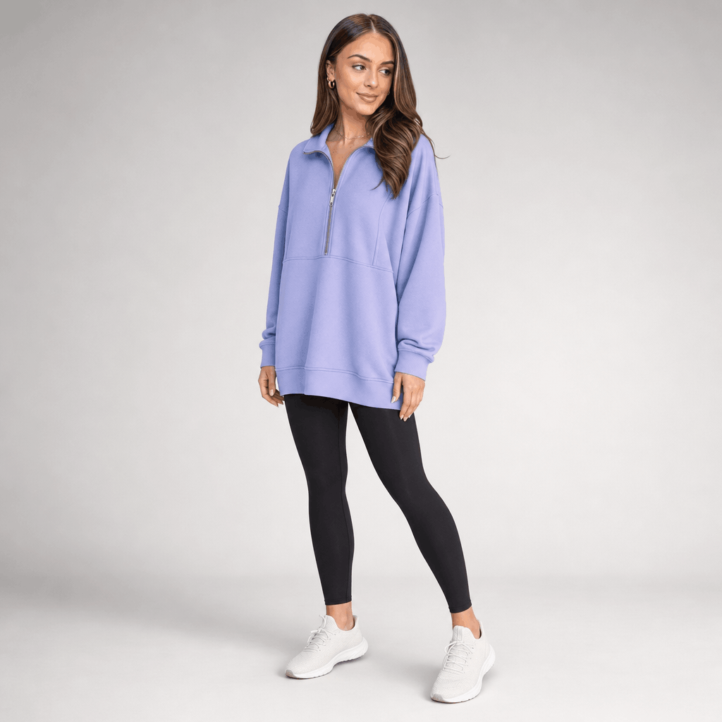 Full-body view of a female model wearing the light purple quarter-zip pullover with black trousers and white sneakers.