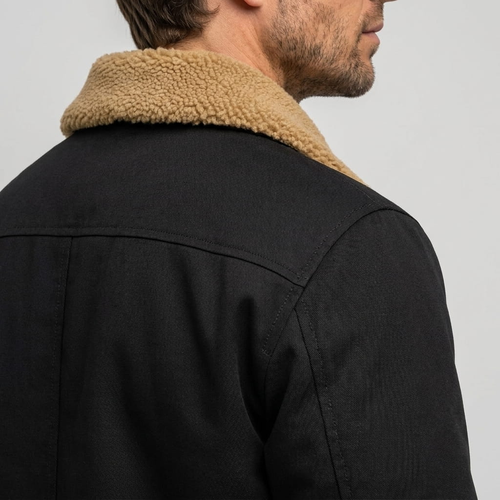 Close-up back and side view of the black bomber jacket, highlighting the contrasting collar and shoulder seams.