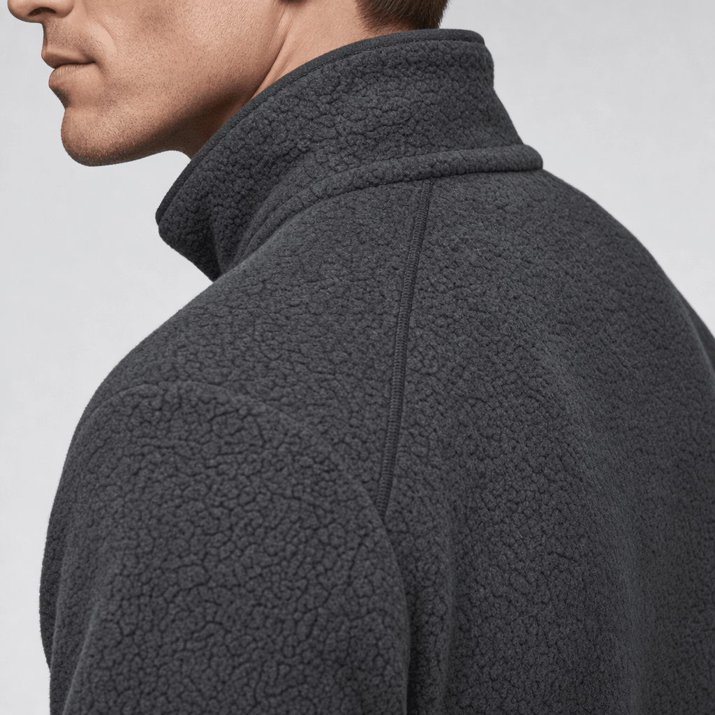 Close-up side view of the dark charcoal fleece jacket, showing the stand collar and textured fabric.