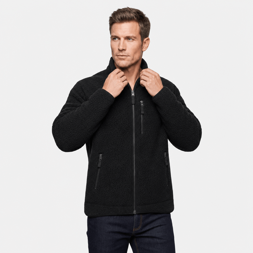 Male model adjusting the stand collar of the dark charcoal zip-up fleece jacket.