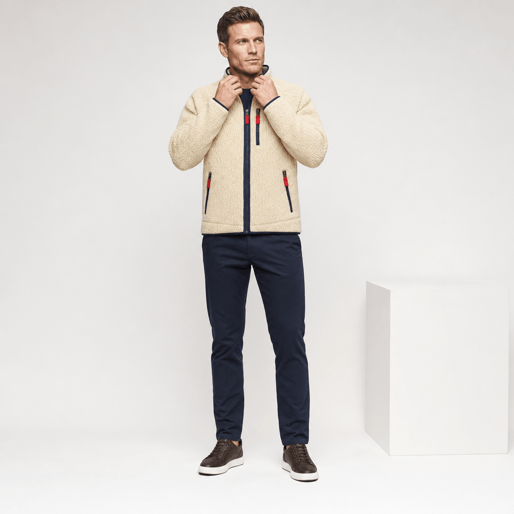 Full-body view of a male model wearing the cream fleece jacket with dark trousers.