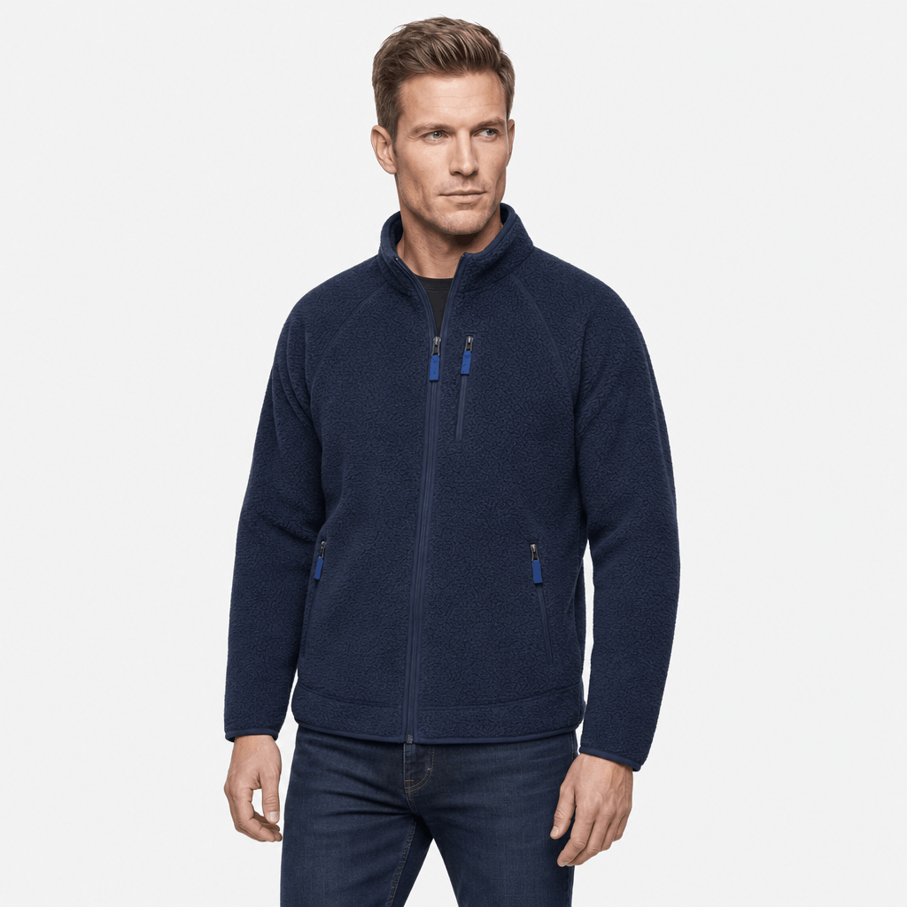 Male model wearing a navy blue fleece zip-up jacket with dark trim and contrasting zippered pockets.
