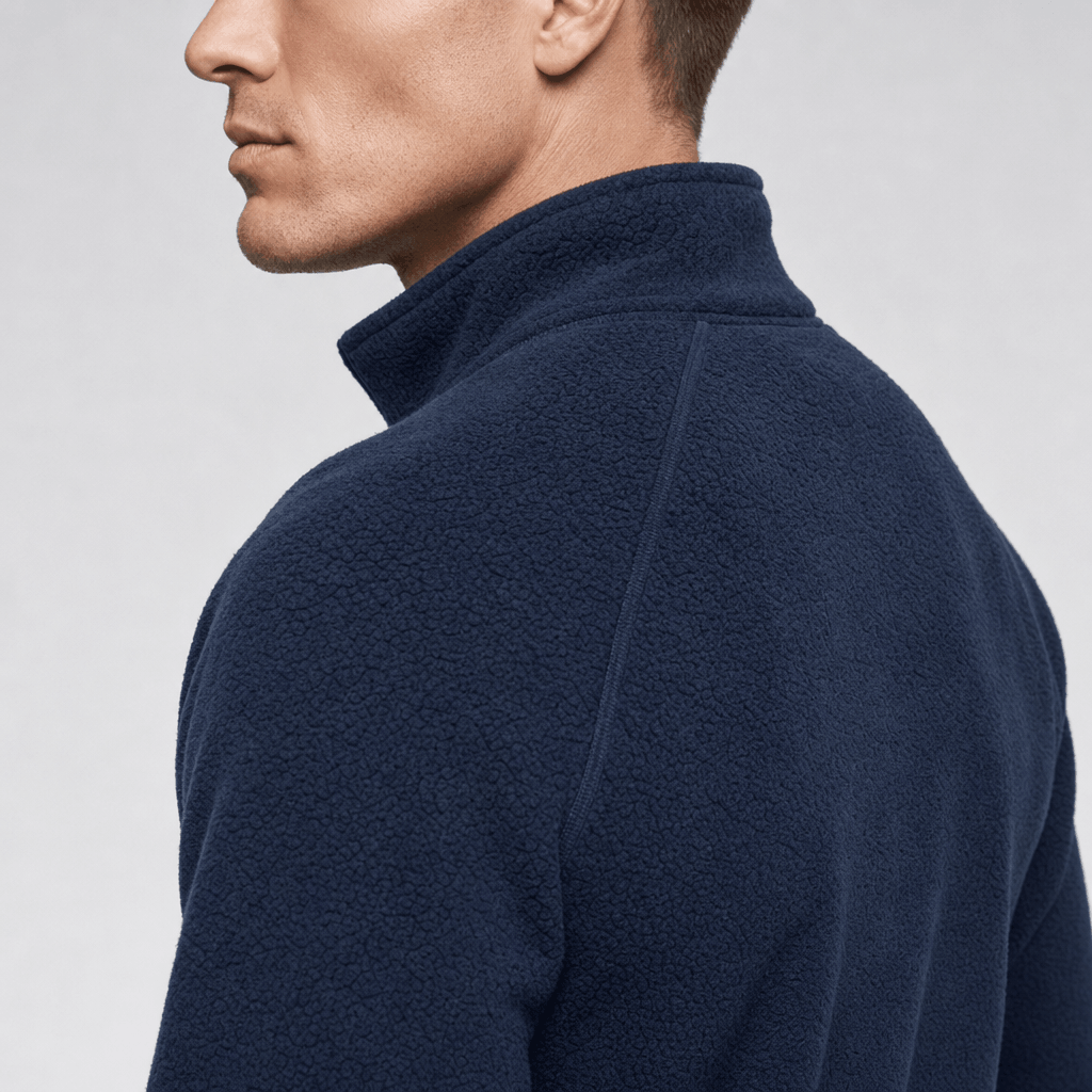 Back and side close-up of the navy blue fleece jacket, showing the high stand collar and textured fabric.