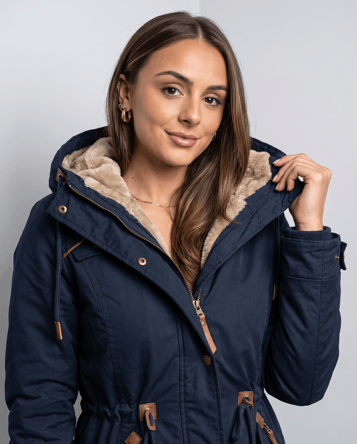 A woman wearing a navy blue winter parka jacket with a hood, plush lining, and drawstring waist