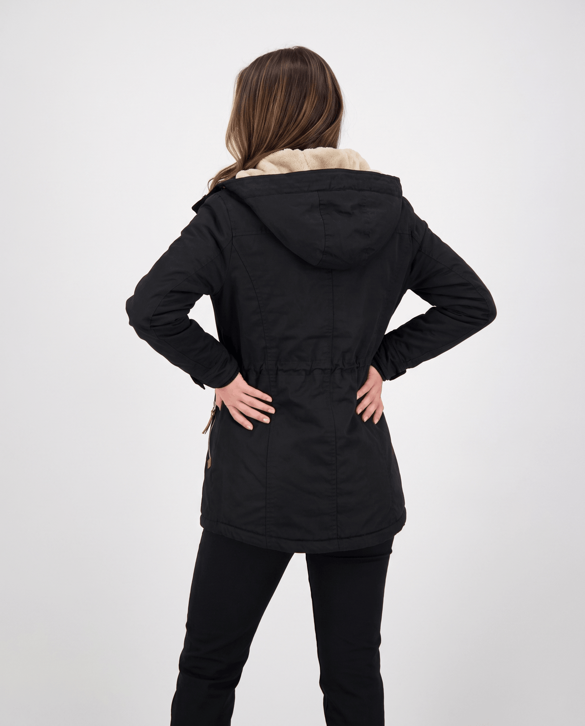 A woman wearing a black winter parka jacket with a hood and drawstring waist, shown from the back