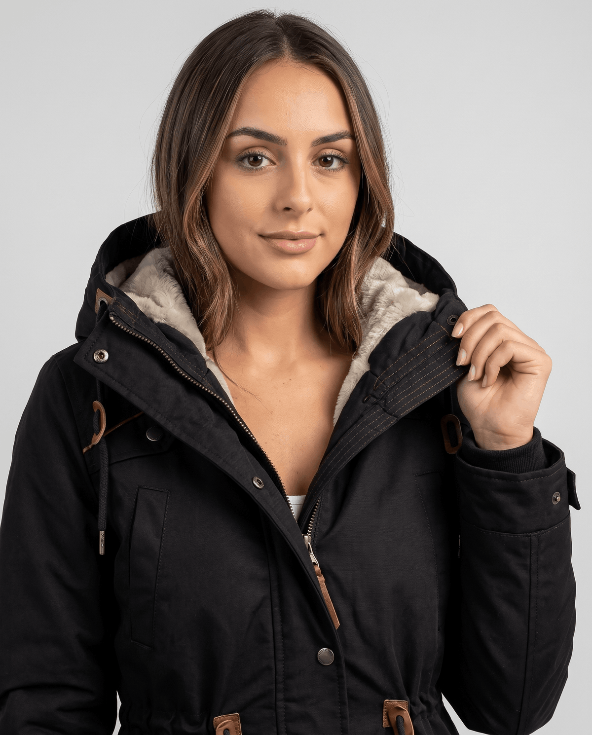 Close-up of a woman wearing a black winter parka jacket, showing the plush-lined hood and drawstring waist