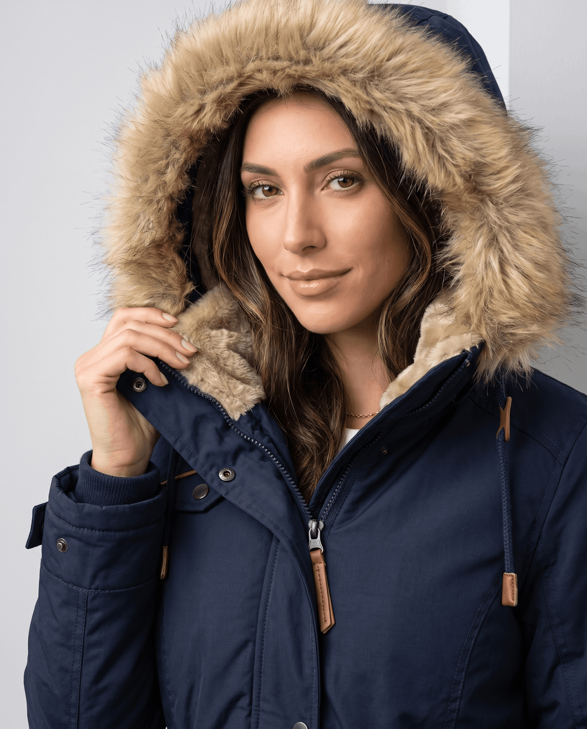Close-up of a woman wearing a navy blue winter parka jacket with a plush-lined hood and drawstring waist
