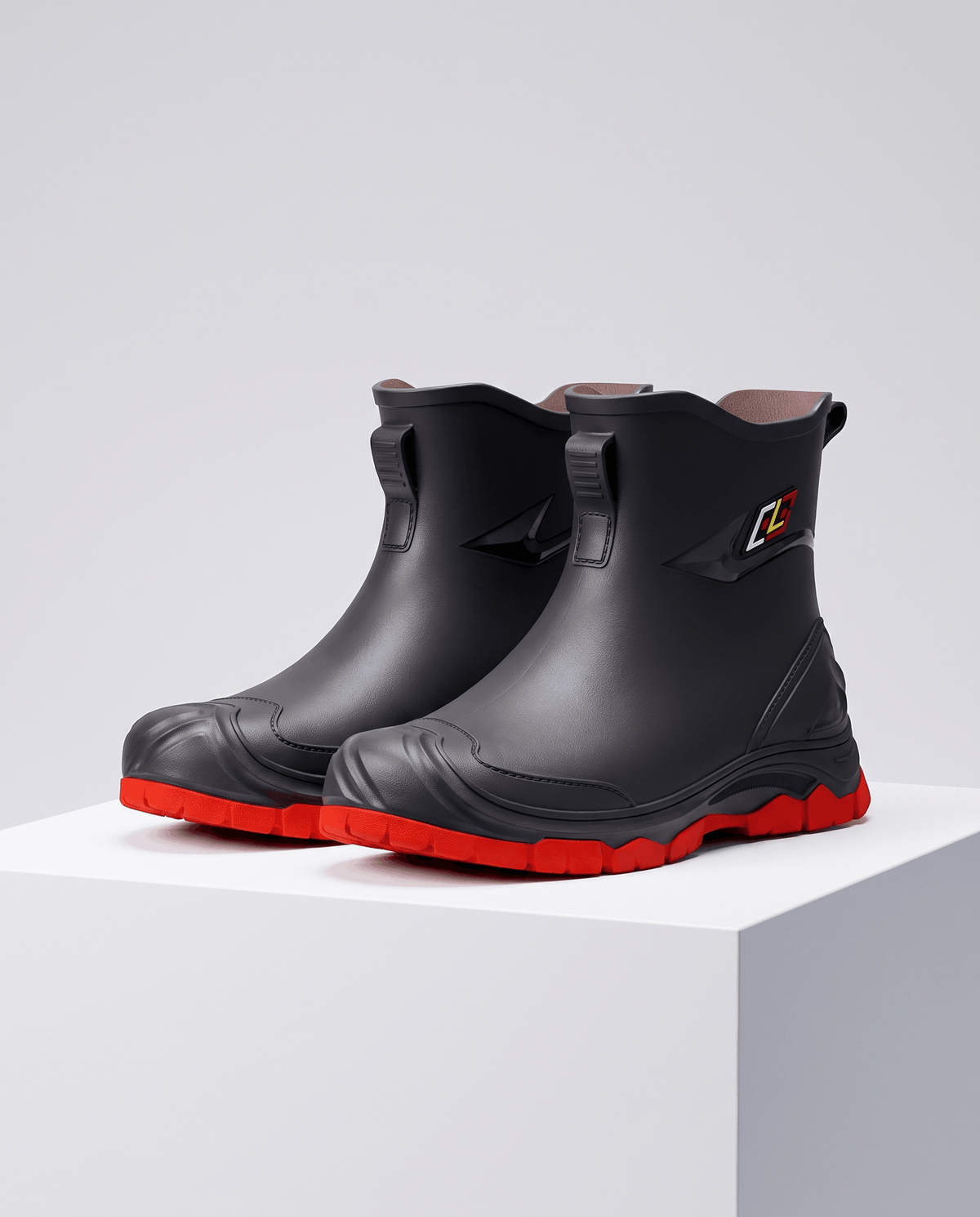 Black rubber boots with red soles standing together on a white display block
