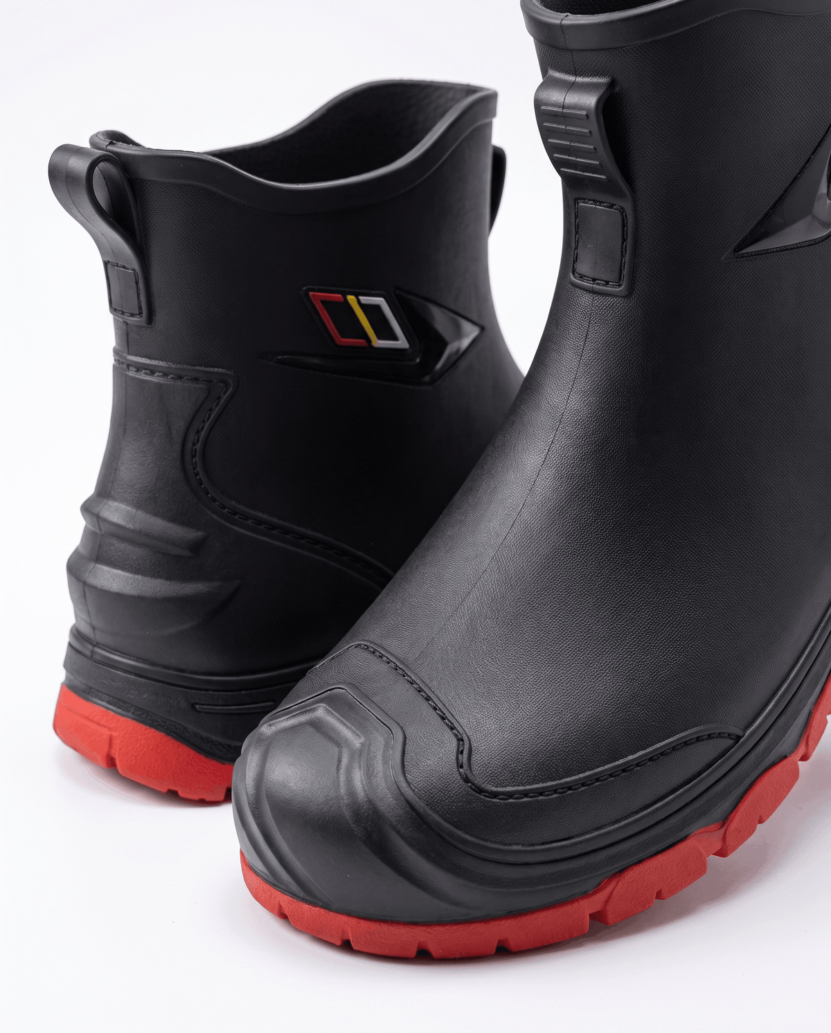 Close-up of the rear pull tab, side logo badge and red sole on a black boot