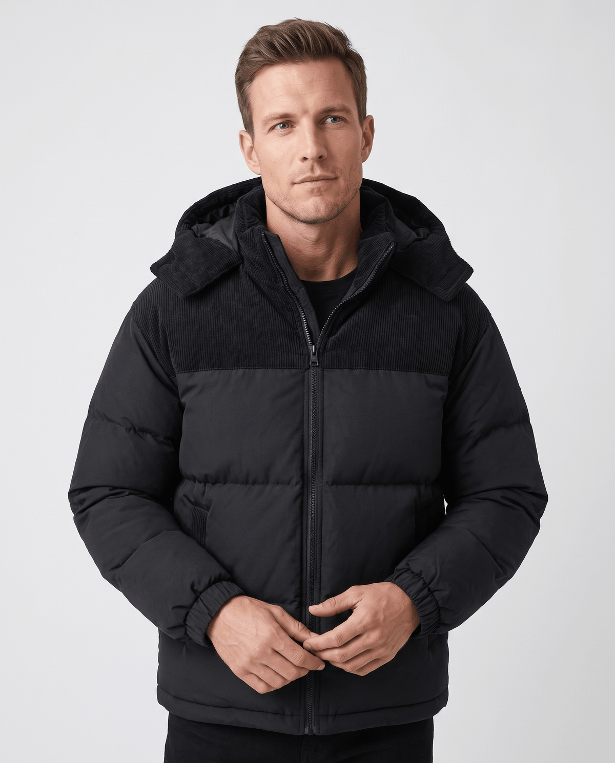 Man wearing black Dravon quilted puffer jacket, front view with corduroy hood and two-tone panels
