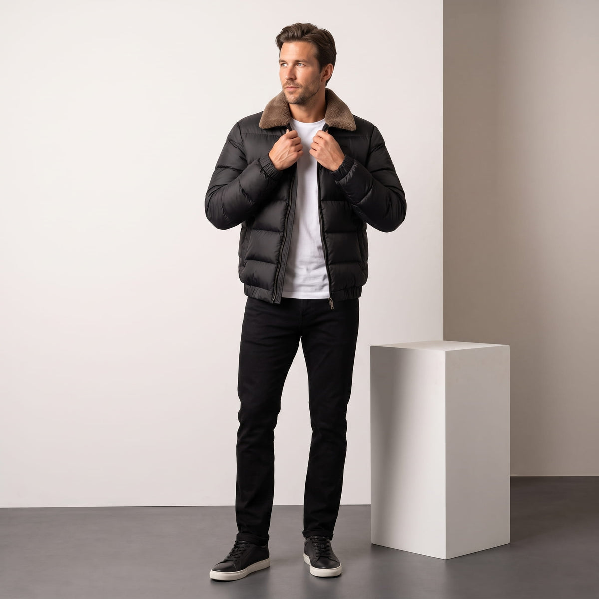 Man fastening a black Julian insulated puffer jacket with dark jeans, full-length view