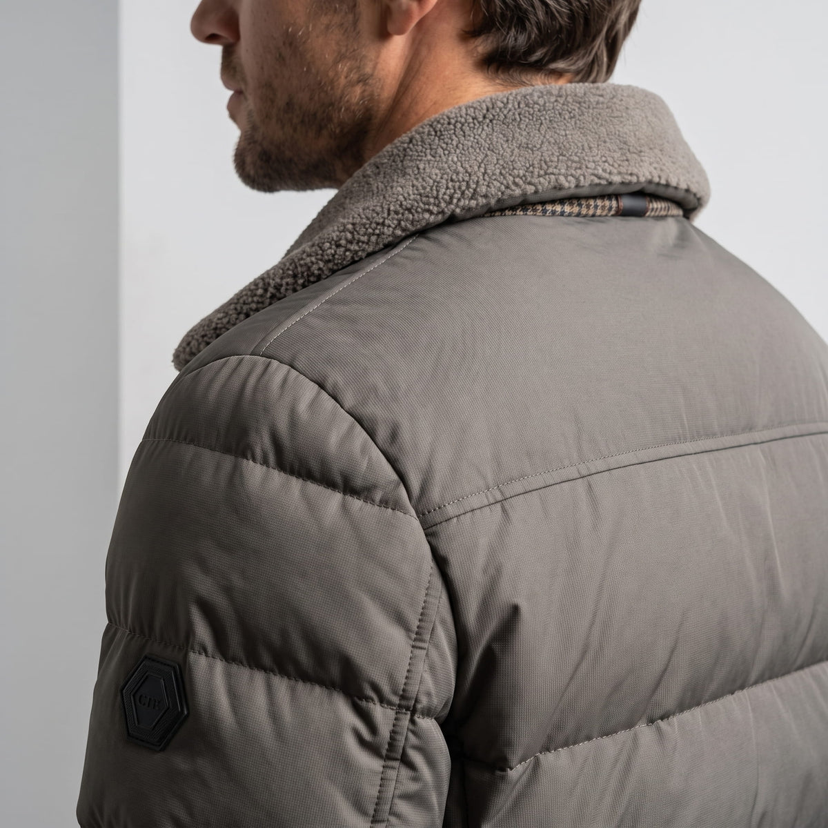 Close-up of gray Julian puffer jacket chest badge and quilted panels