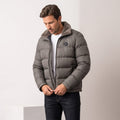 Man zipping a gray Julian insulated puffer jacket with jeans, full-length view