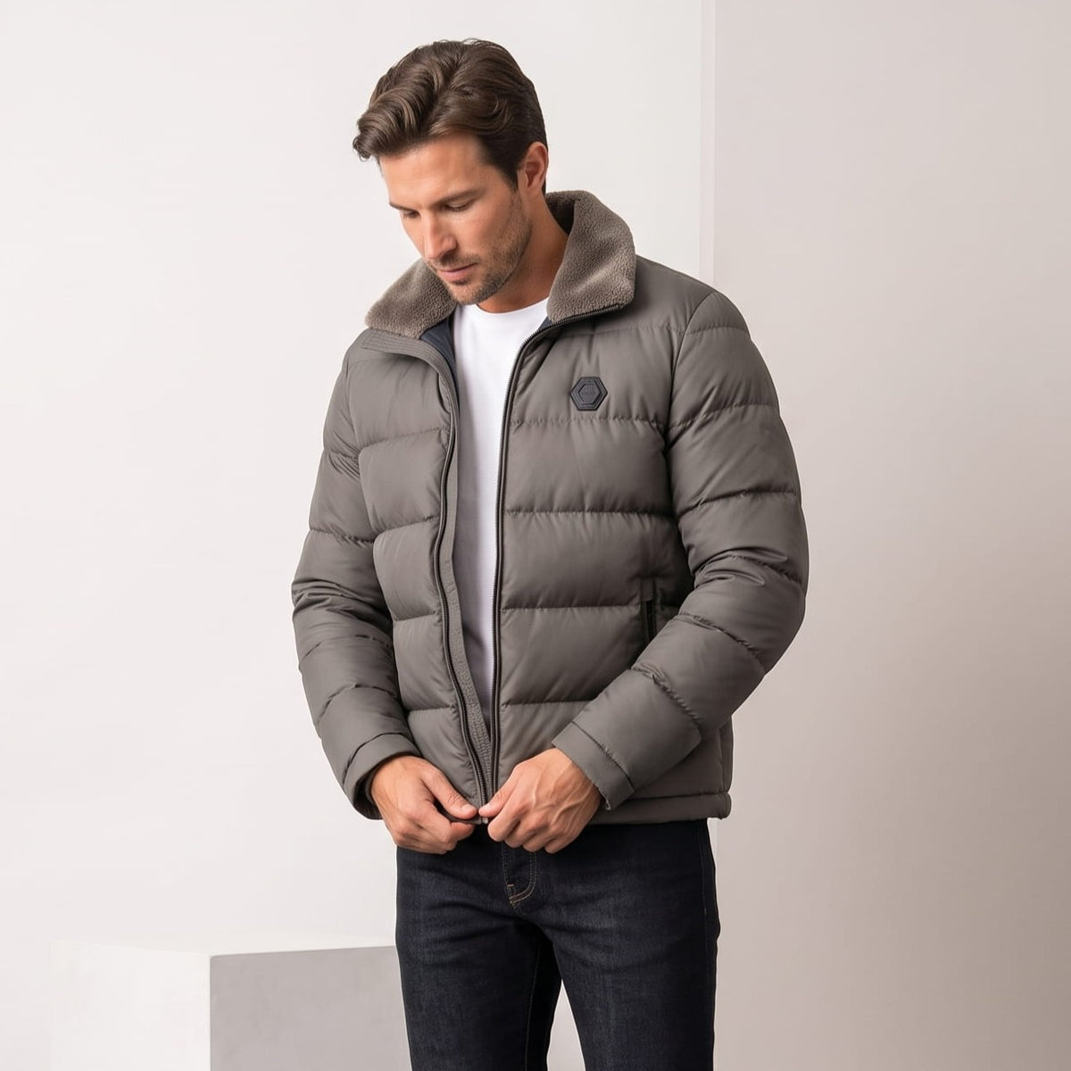 Man zipping a gray Julian insulated puffer jacket with jeans, full-length view