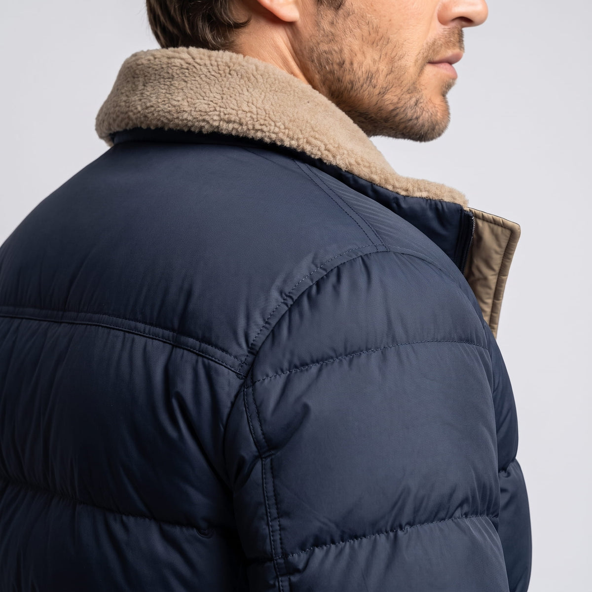 Close-up of navy blue Julian puffer jacket fleece collar and quilted shoulder from behind