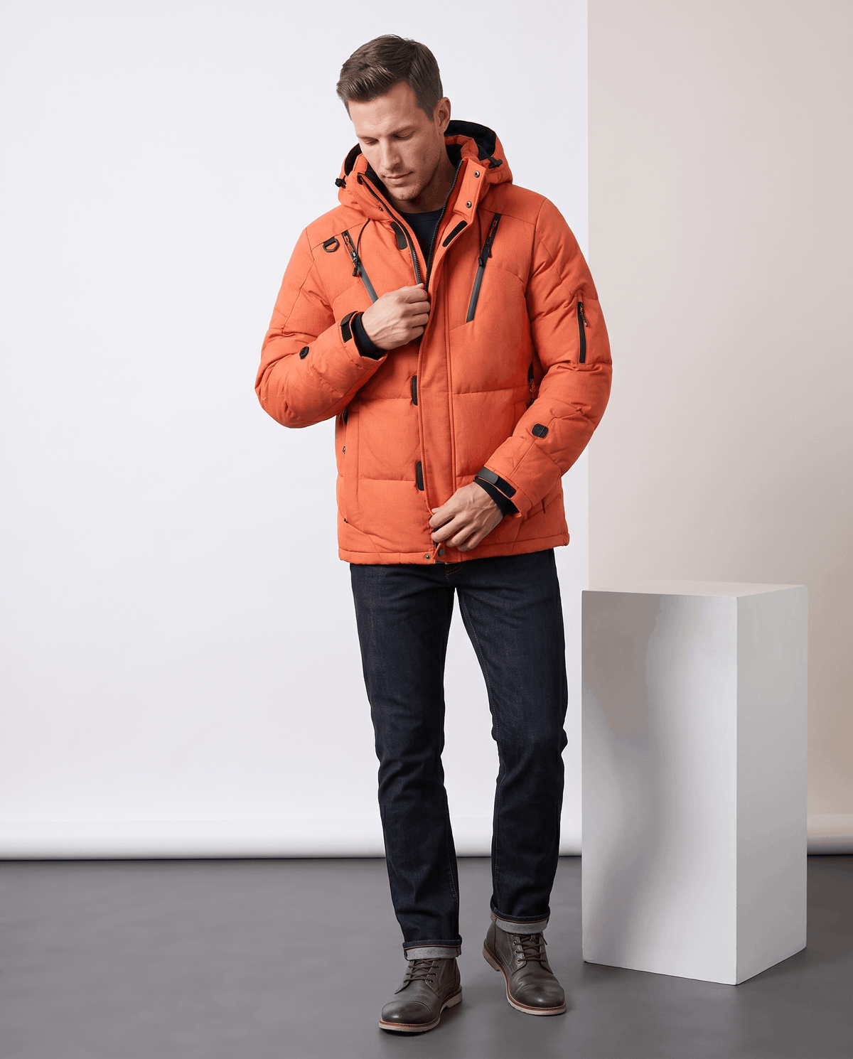 Man wearing orange Paolo hooded puffer jacket with jeans, full-length front view