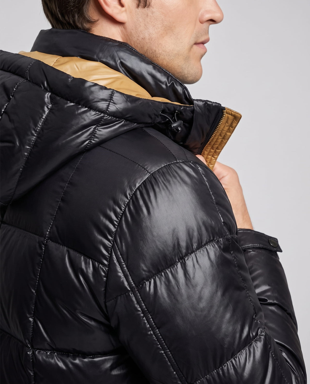 Close-up of black Robin puffer jacket hood and padded shoulder from behind