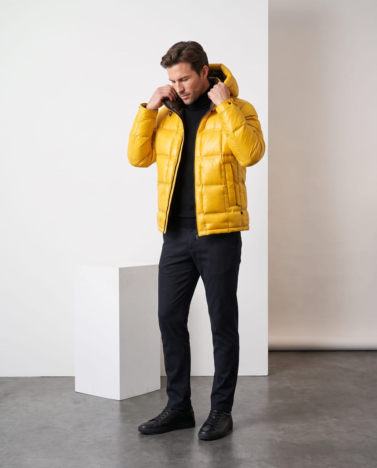 Man wearing yellow Robin hooded puffer jacket, full-length view adjusting the hood