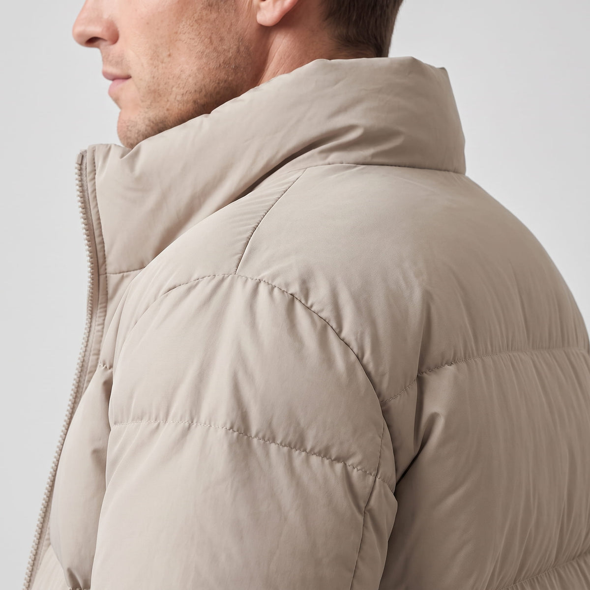 Close-up of beige Salvador puffer jacket quilted shoulder and high collar from behind