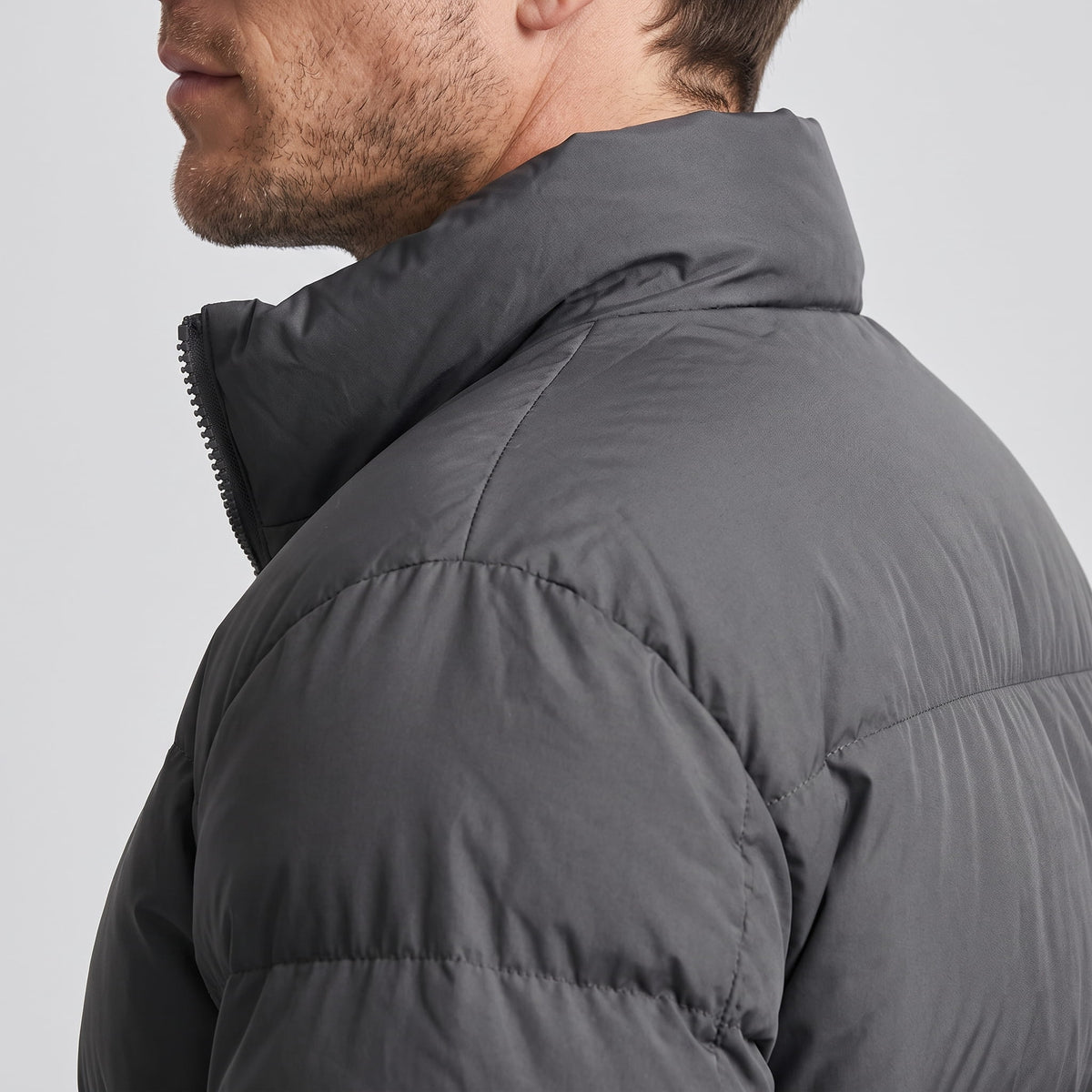Close-up of dark gray Salvador puffer jacket high collar and quilted shoulder panel