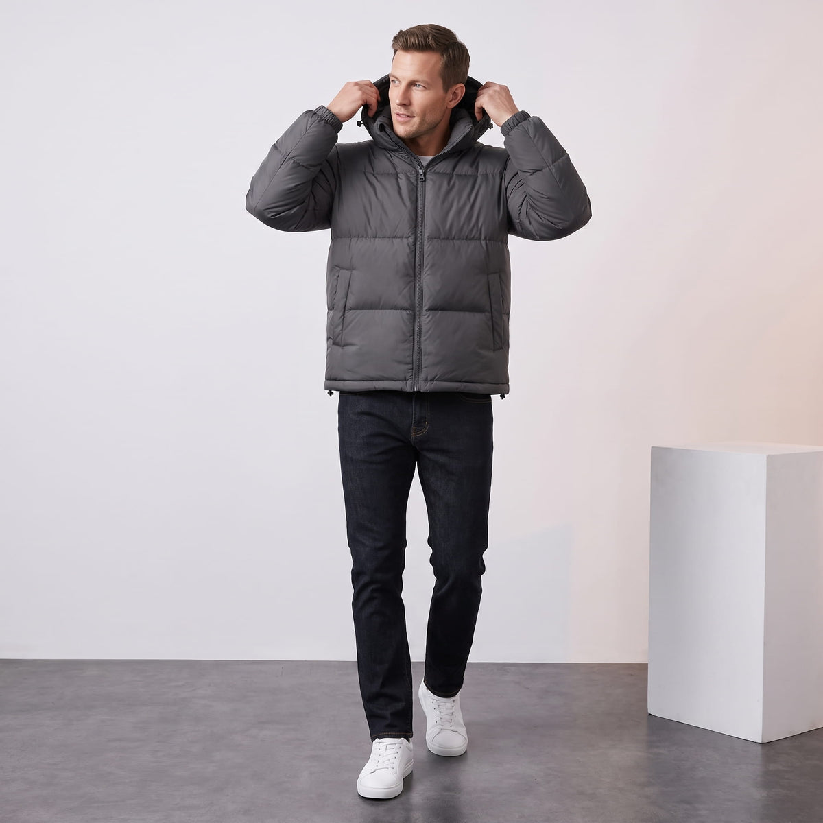 Man pulling up the hood of a dark gray Salvador insulated puffer jacket, full-length view