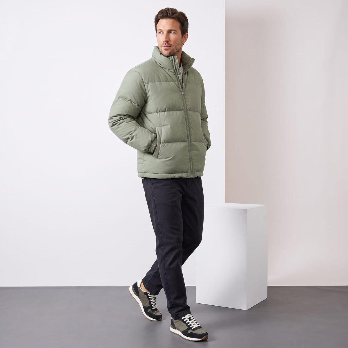 Man walking in a sage Salvador quilted puffer jacket with dark trousers, full-length view