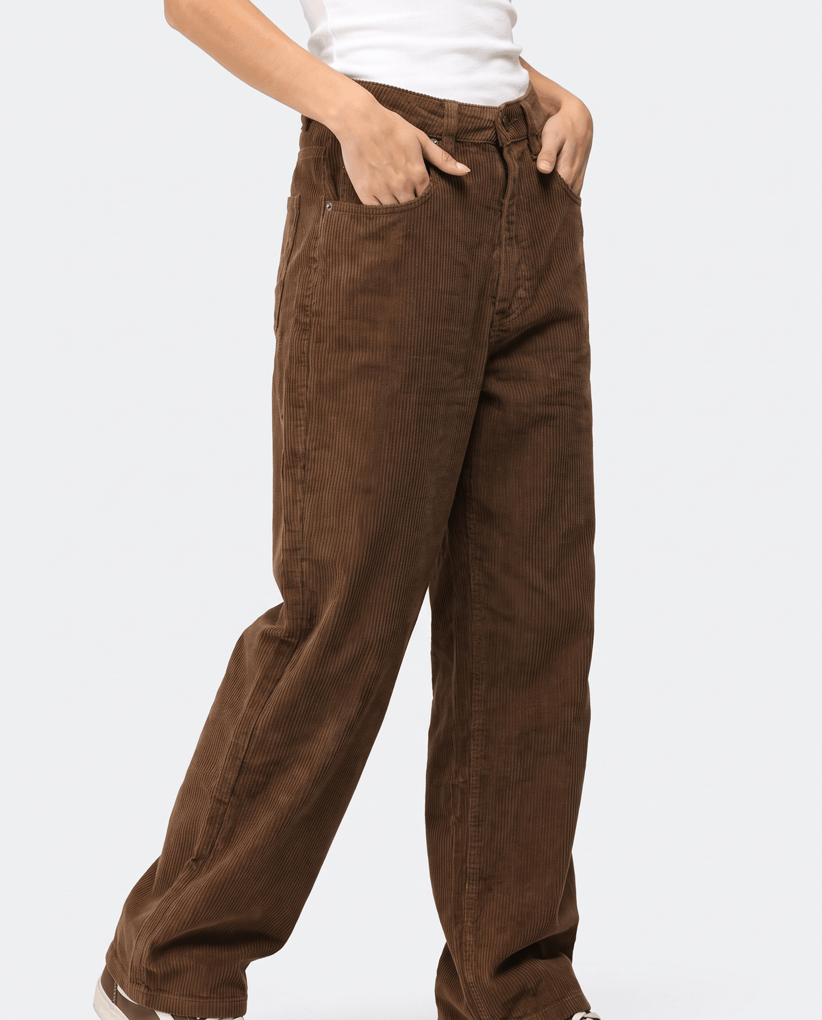 Angled front view of brown cord trousers with hands in the front pockets mid-step