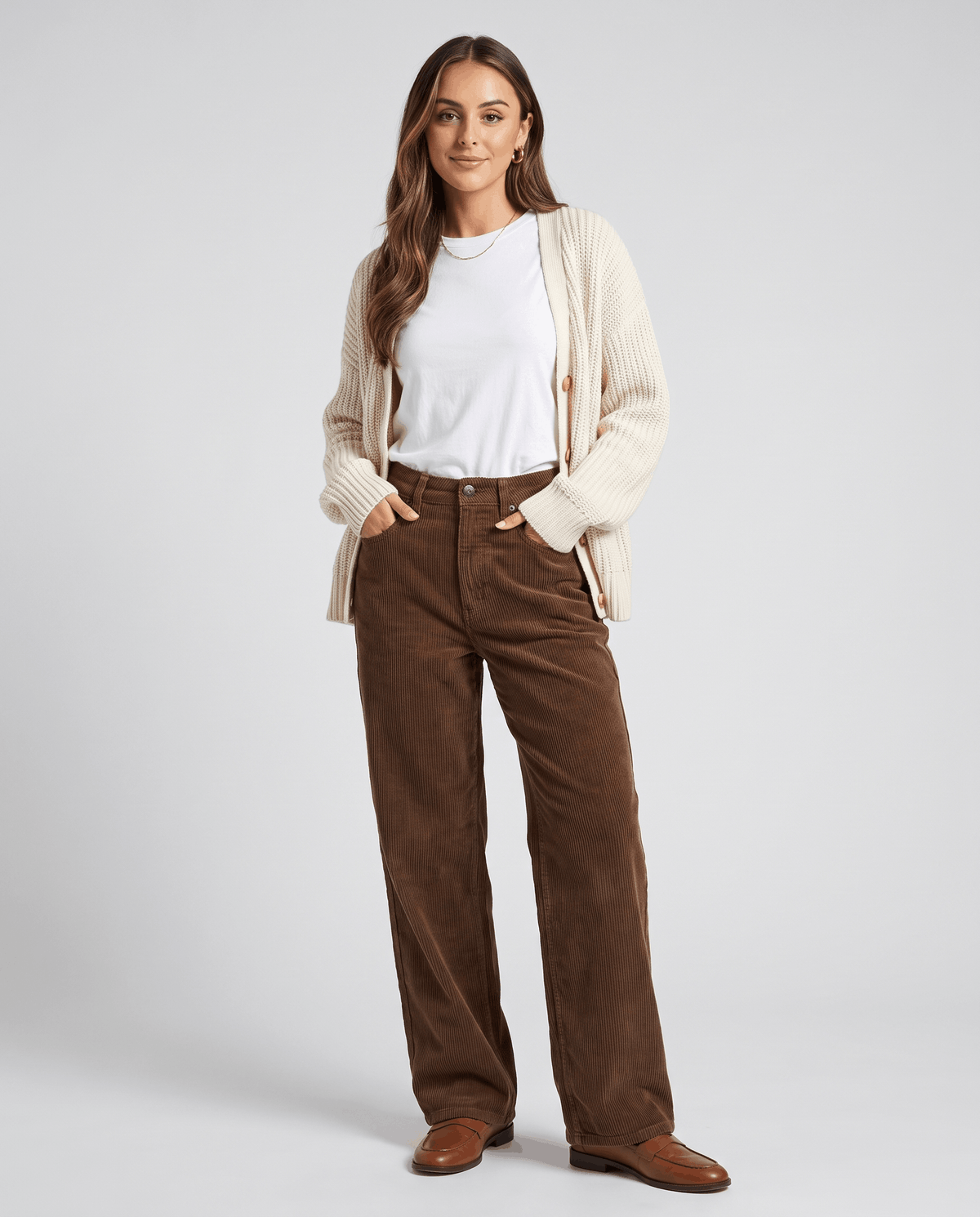 Model in brown ribbed trousers styled with a cream cardigan, white tee and brown shoes