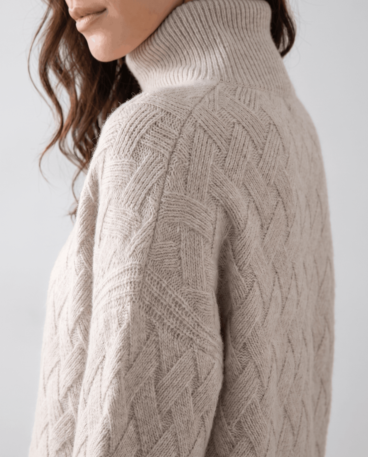 Shoulder detail of beige knit showing raglan seam and woven pattern