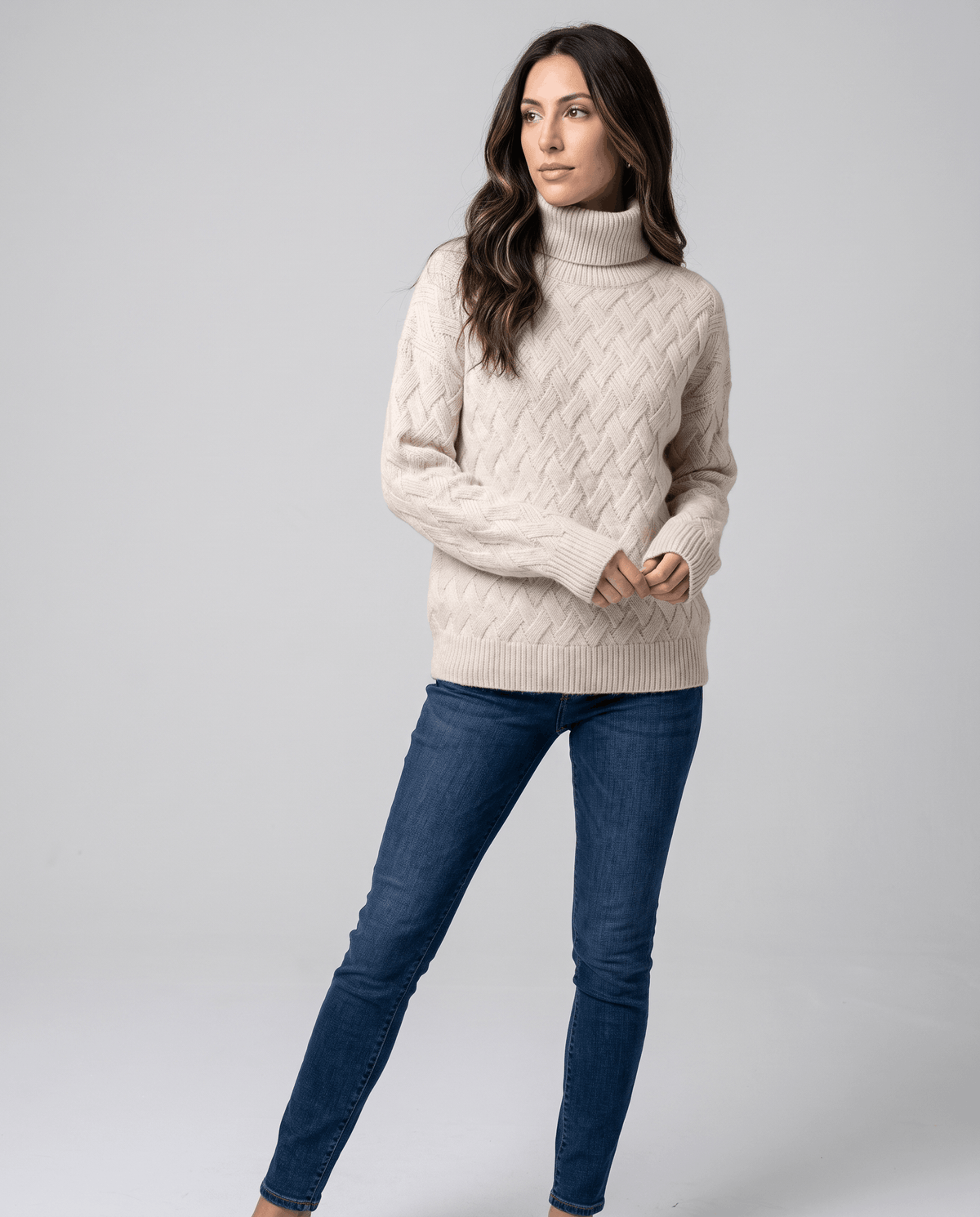 Front view of beige basketweave turtleneck worn with dark skinny jeans