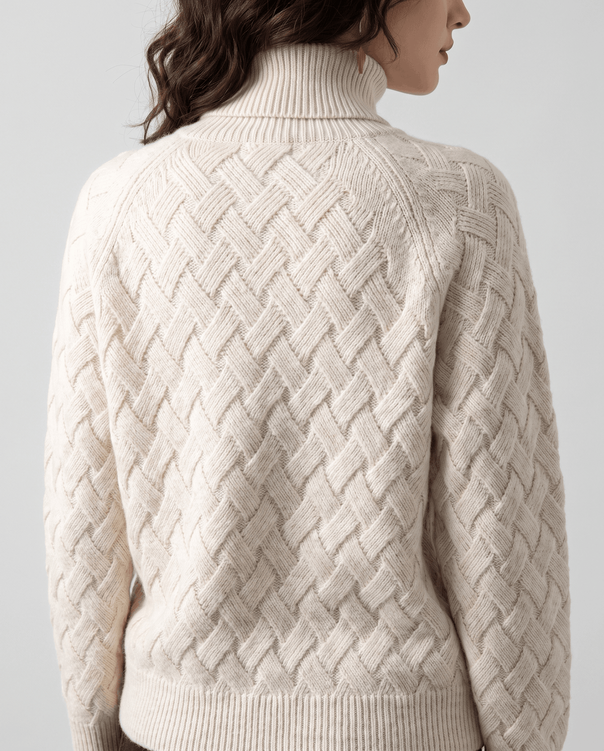 Back view of cream basketweave sweater showing raglan seams and ribbed hem