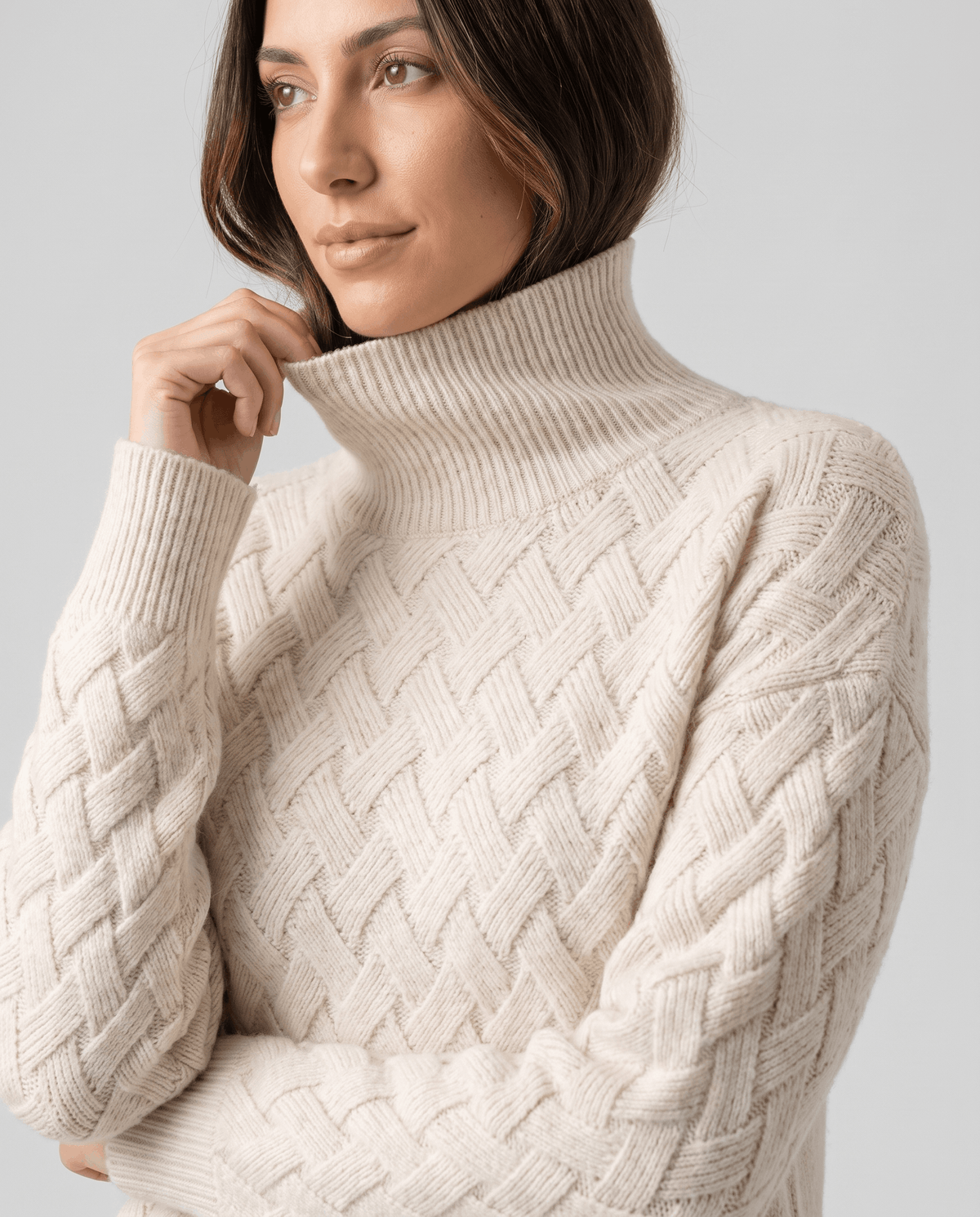 Close-up of model touching the folded collar of a cream woven-texture sweater