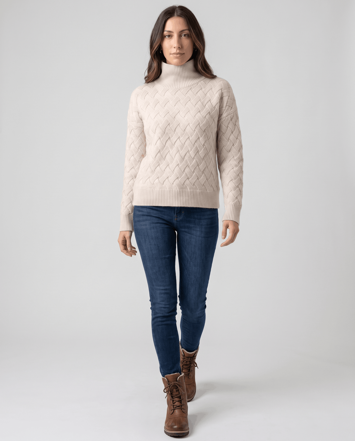 Full-length view of cream turtleneck sweater with blue jeans and brown boots