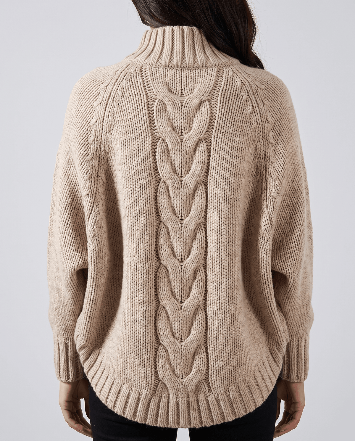 Back view of beige batwing sweater showing center cable and curved hem