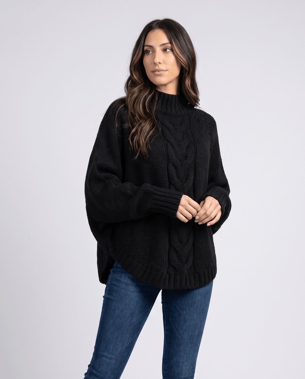 Front view of black cable knit turtleneck with light wash jeans
