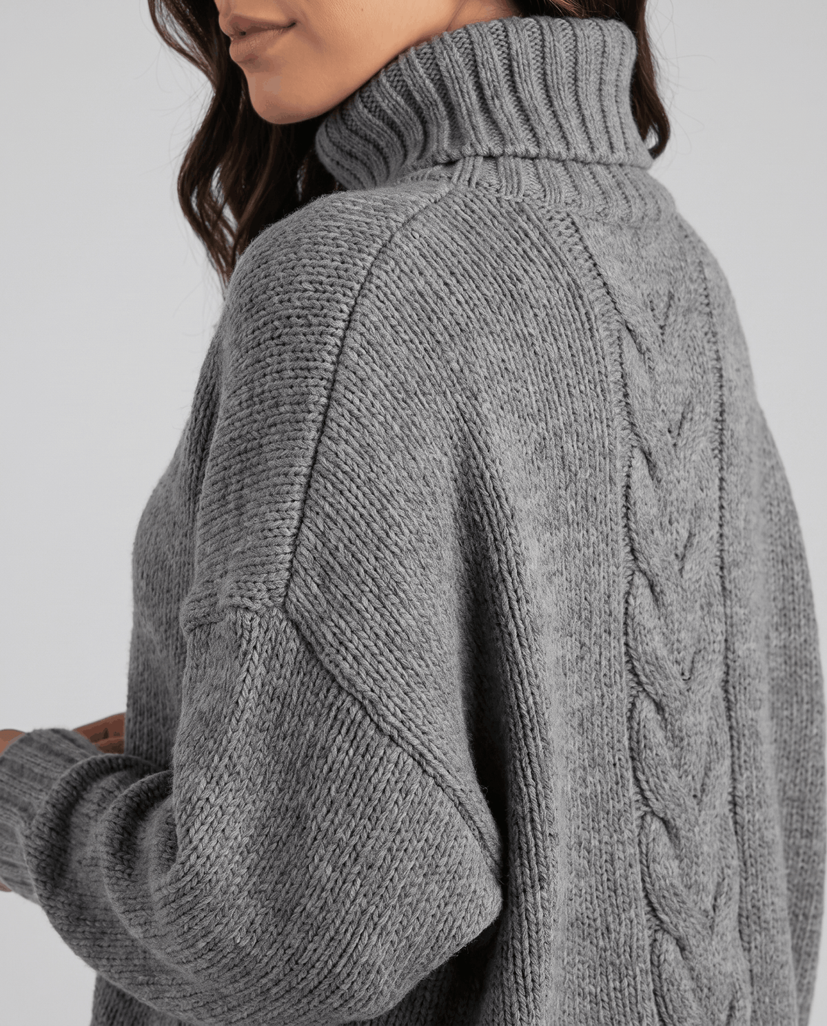 Side shoulder detail of gray cable knit with tall folded neck