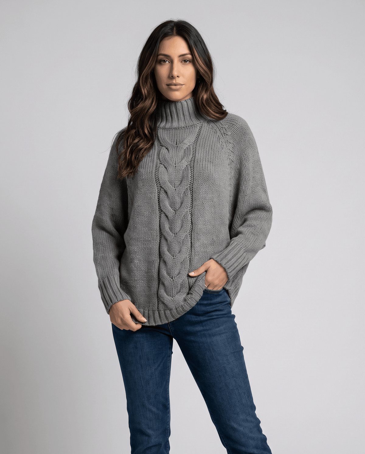 Front view of gray batwing cable sweater worn with dark jeans