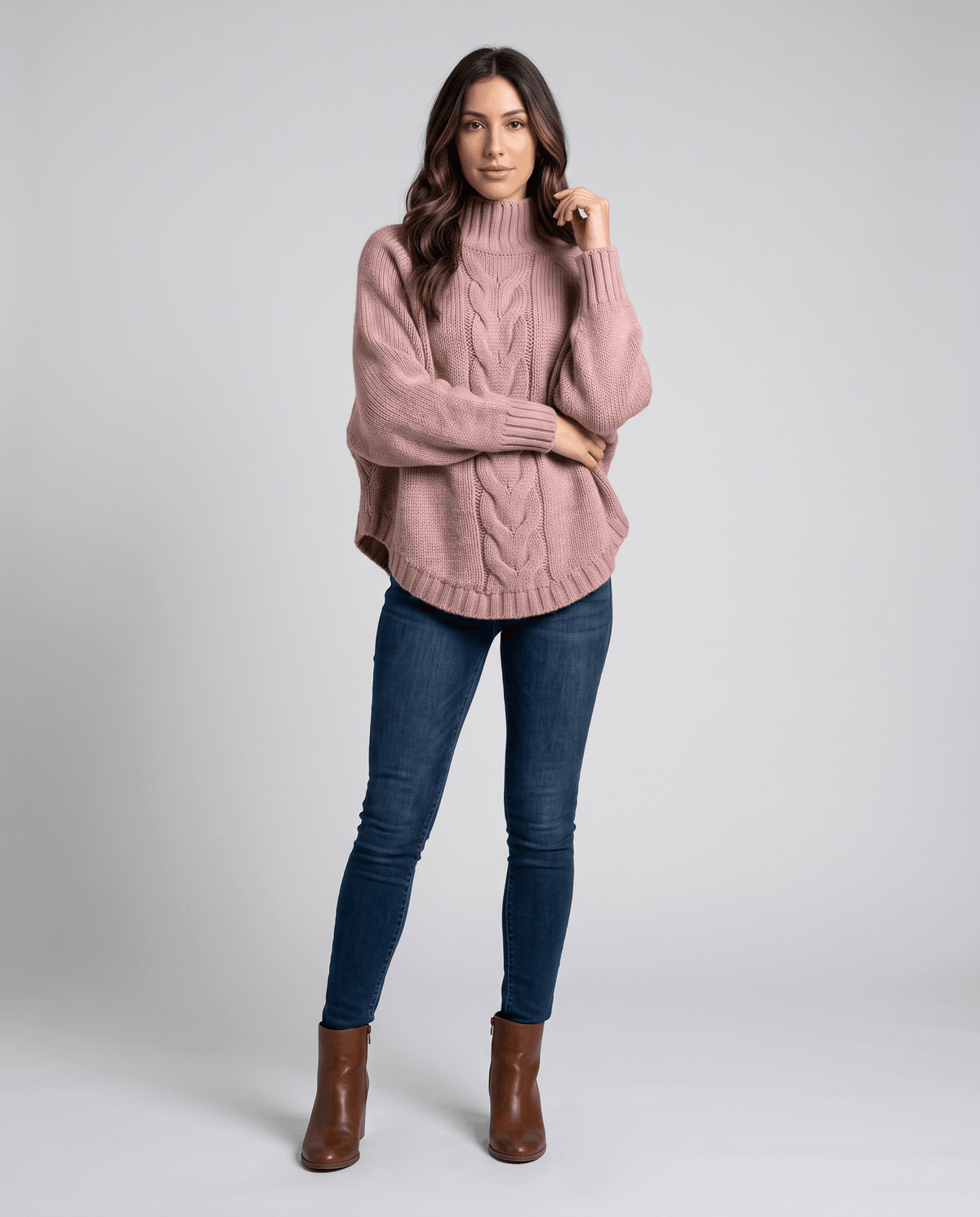 Full-length view of pink turtleneck sweater with blue jeans and brown boots