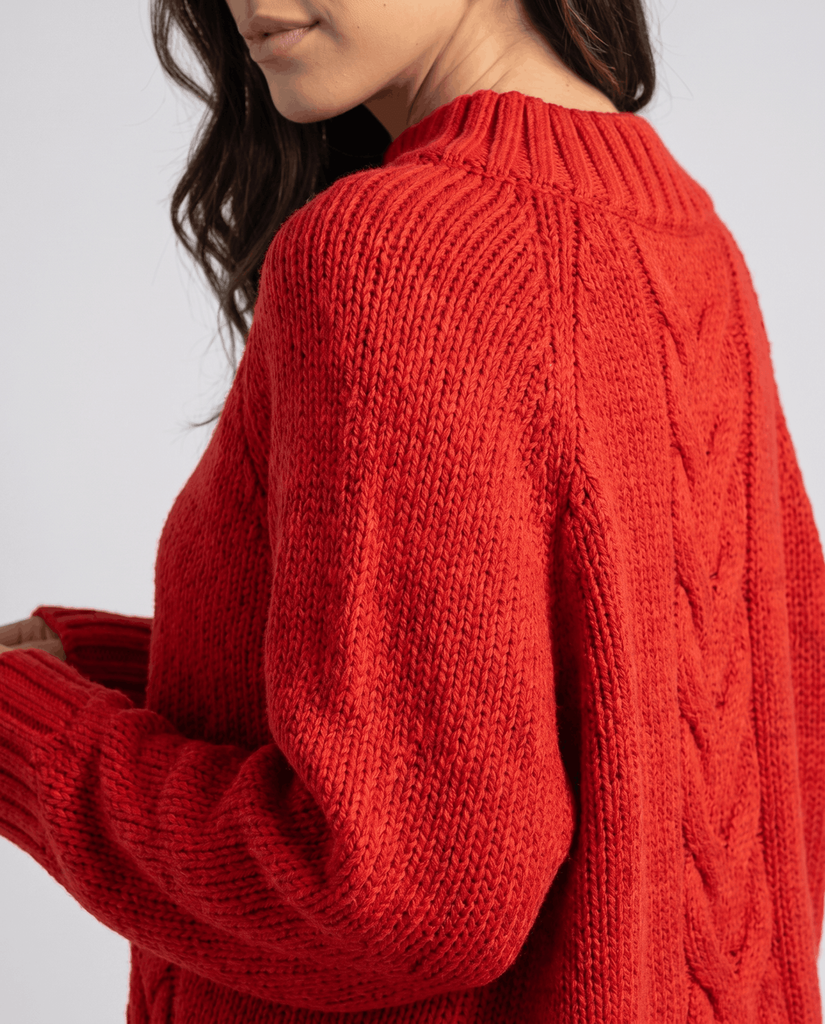 Shoulder detail of red chunky knit showing ribbed neck and raglan seam