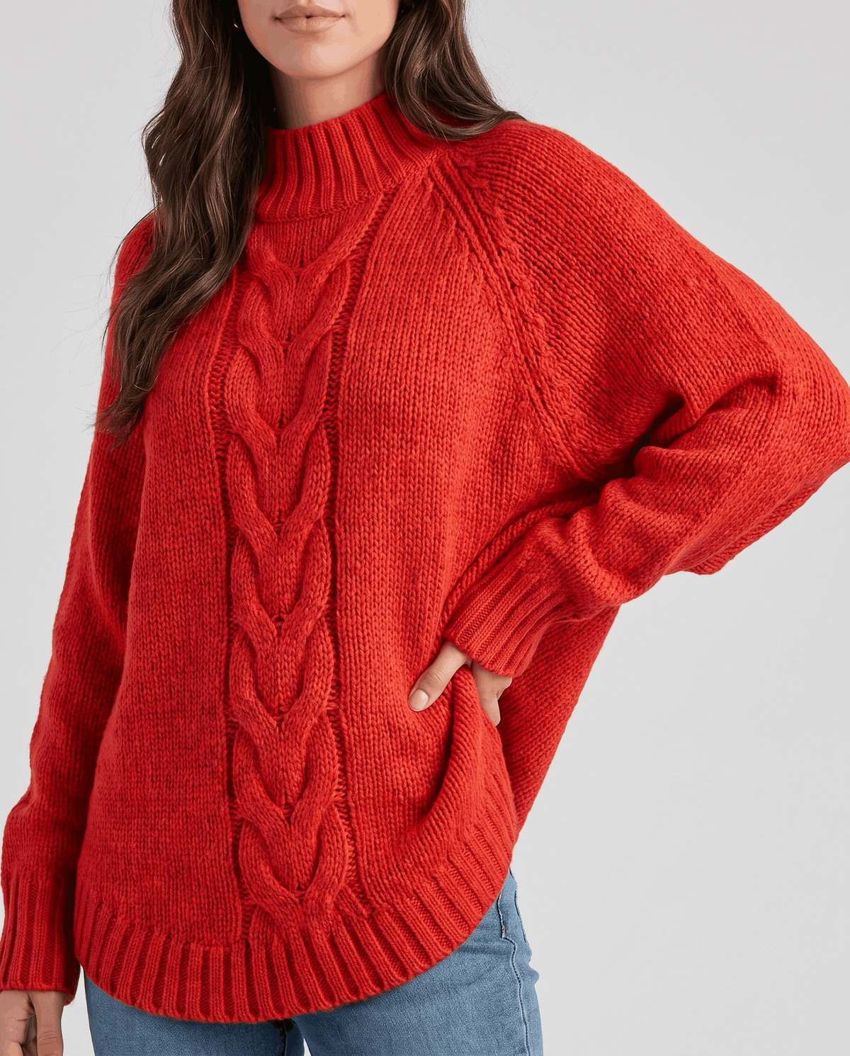 Cropped front view of red cable knit sweater with hand on hip