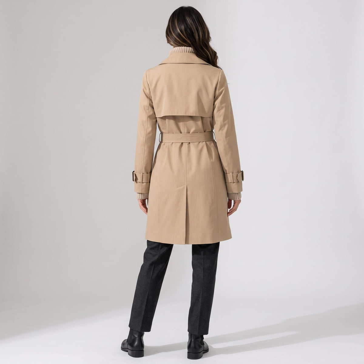 Back view of beige coat cinched at the waist with its buckled belt