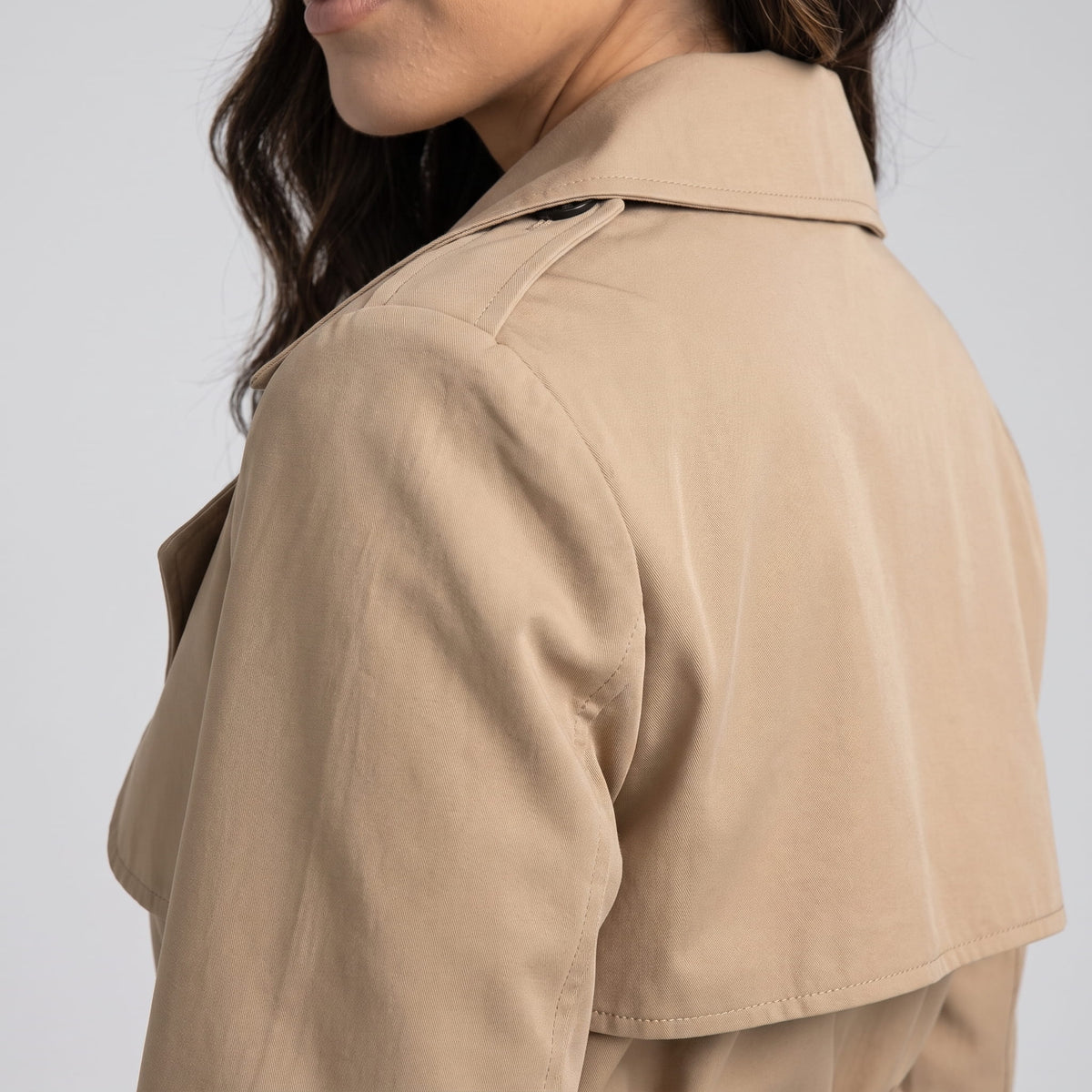 Rear shoulder detail of beige coat showing the epaulette and back storm flap