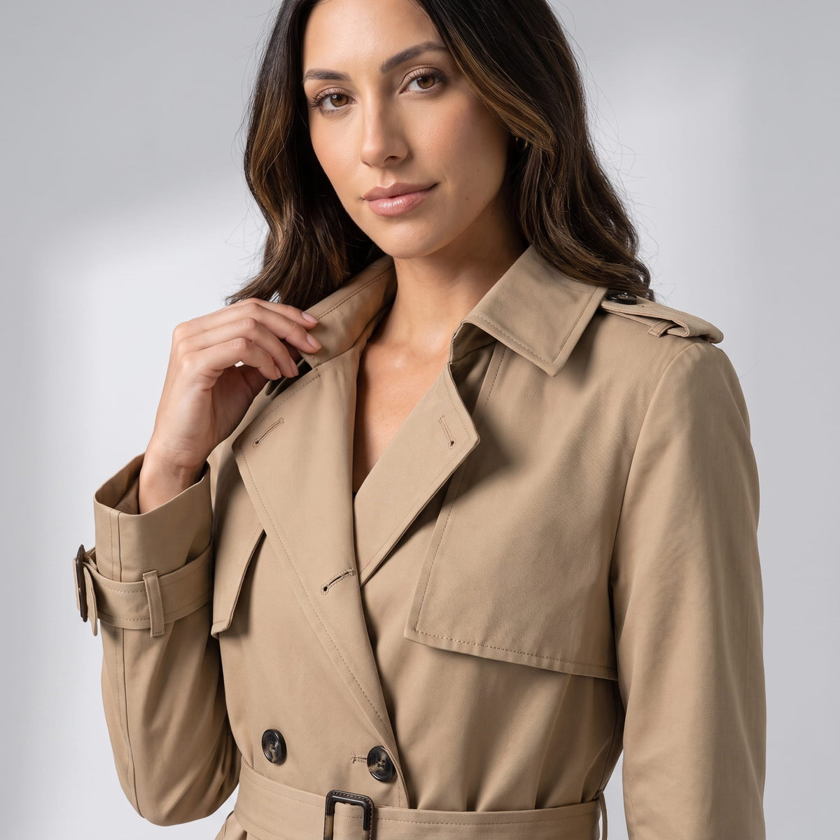 Close-up of beige coat collar with shoulder epaulette, storm flap and buckled belt