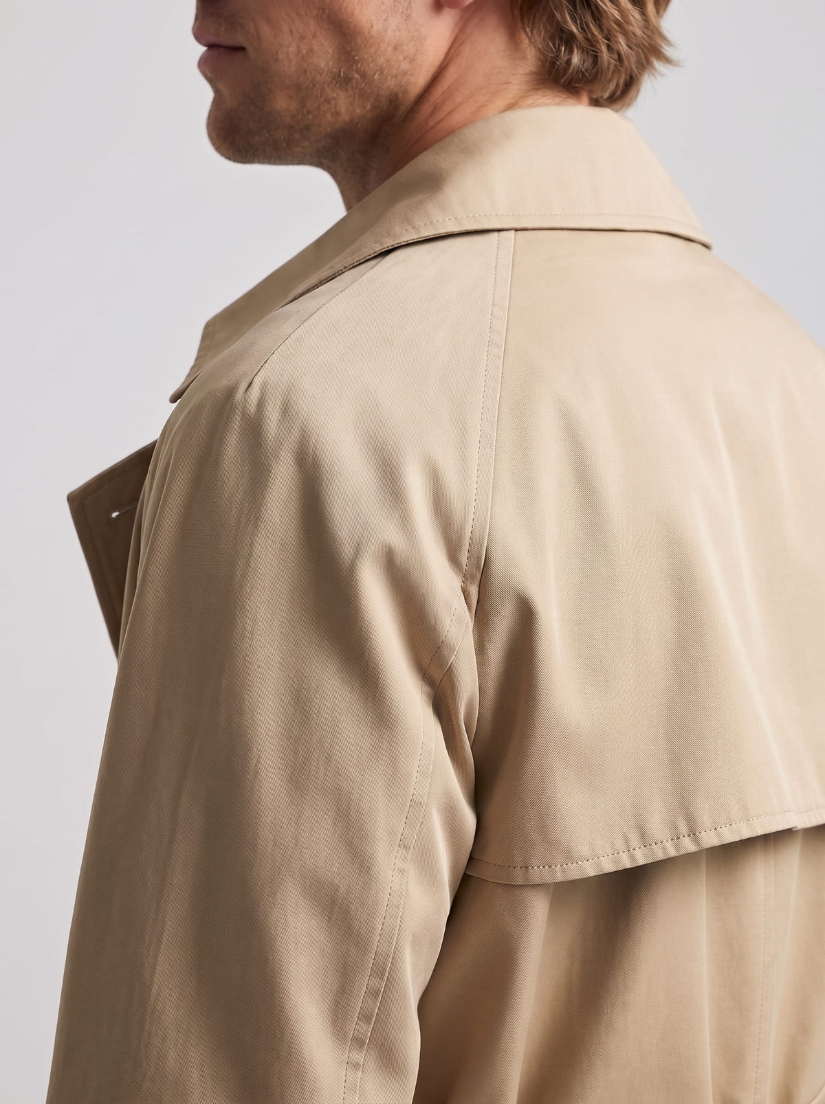 Close-up of beige trench coat storm flap on the shoulder and turn-down collar