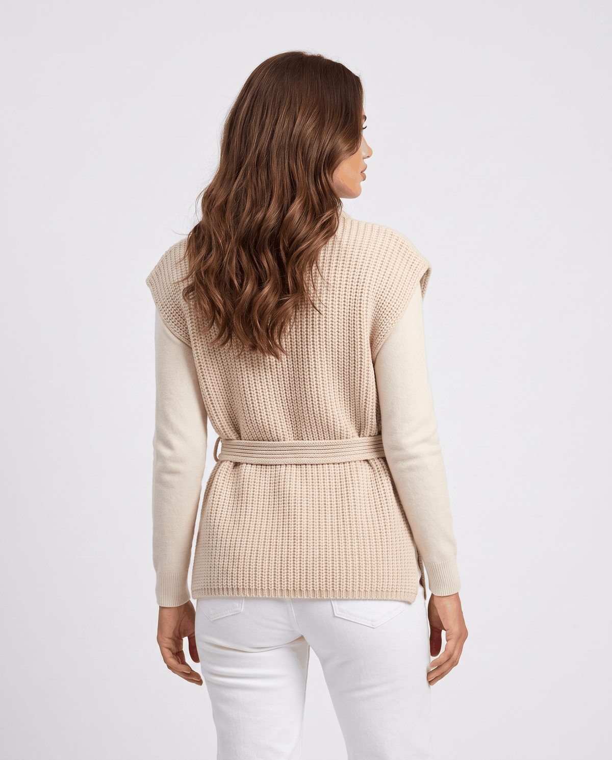 Back view of beige vest with tie belt, worn with white jeans and knit