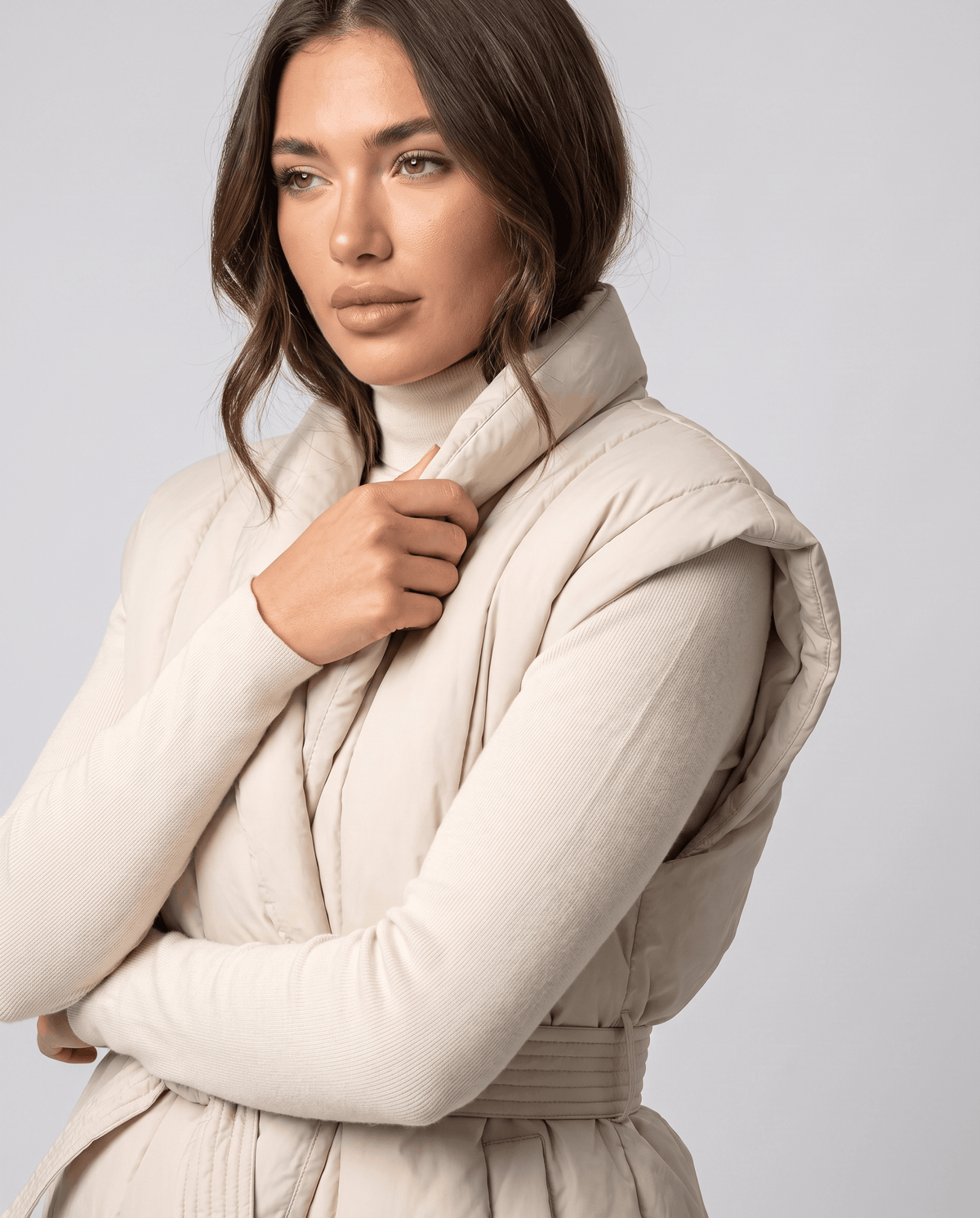 Beige vest close-up with model's hand holding the draped shawl collar