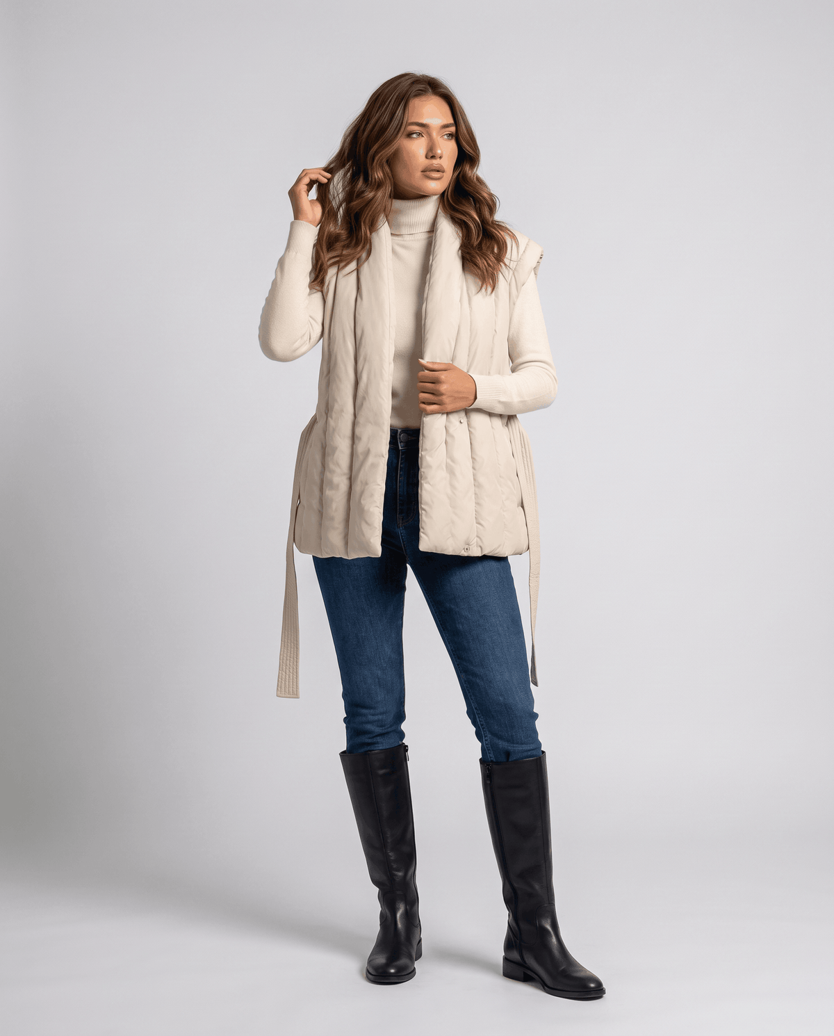 Full-length beige vest styled with jeans and black boots, tie belt at waist