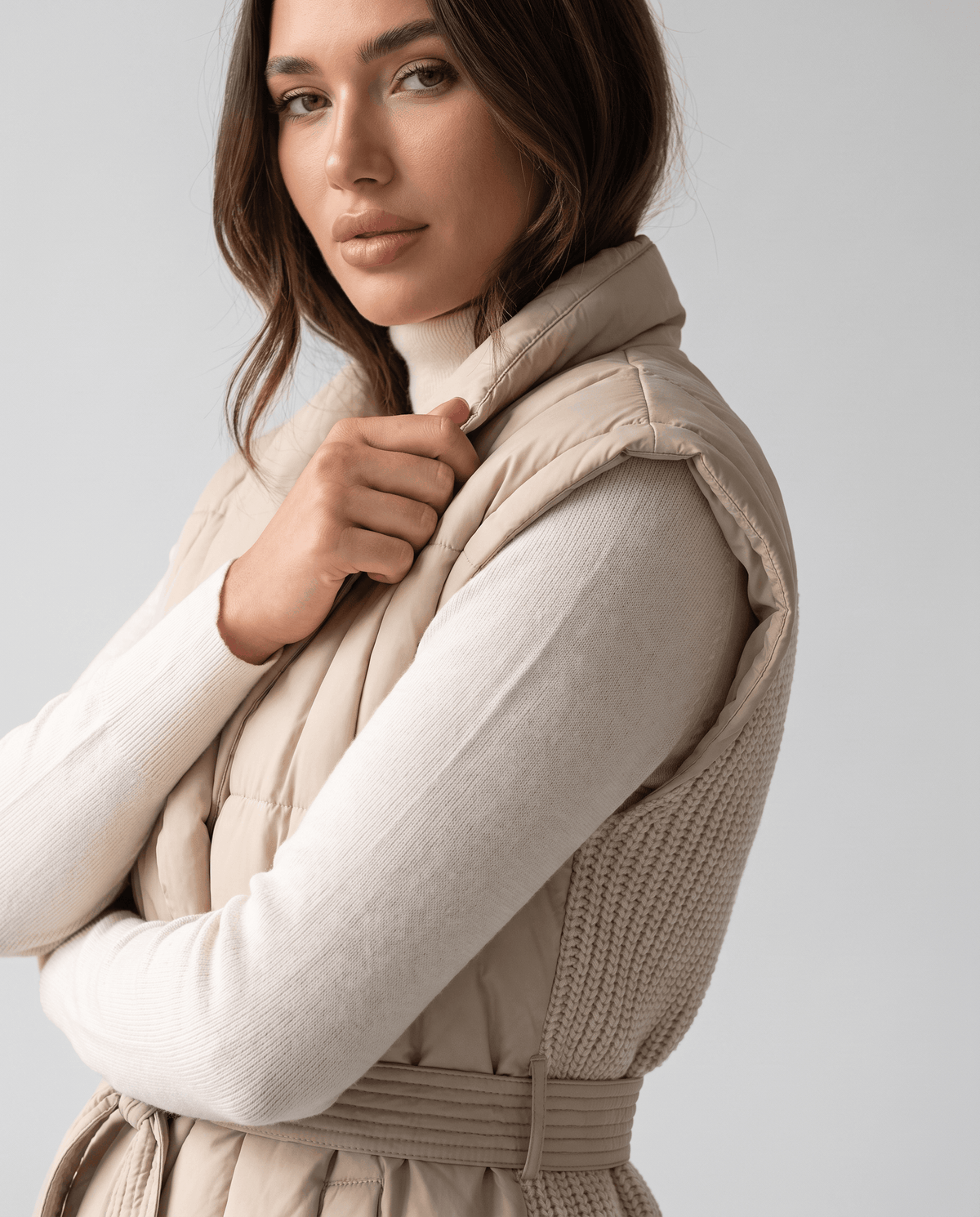 Khaki vest close-up worn over white knit, showing shawl collar and belt