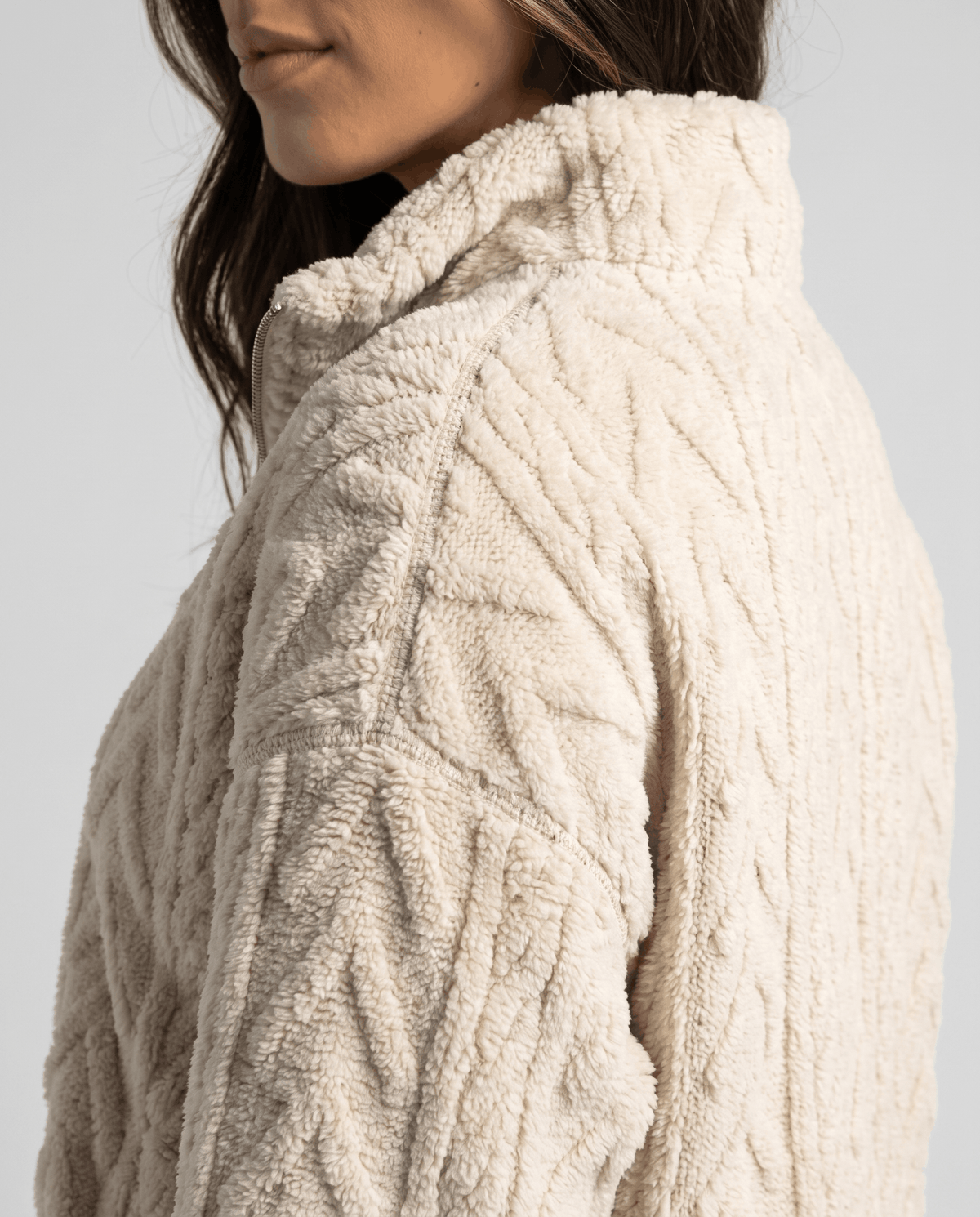 Shoulder detail of cream fleece showing cable texture and stand collar
