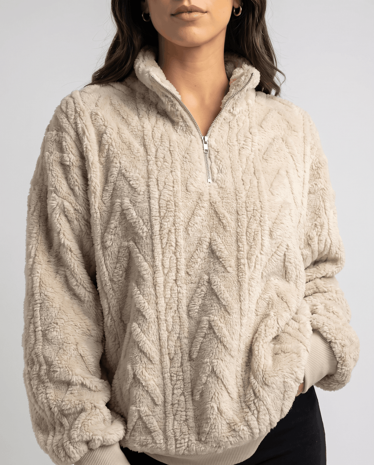 Cropped front view of cream plush pullover with embossed cables and silver zip